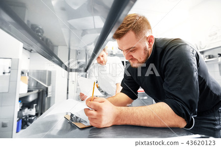 chef and cook with lists or bills at kitchen chef and cook with lists or bills at kitchen 43620123