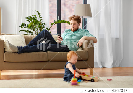 father with smartphone and baby playing at home 43620171