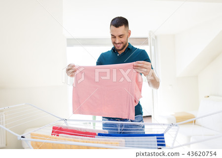 smiling man with laundry and drying rack at home 43620754
