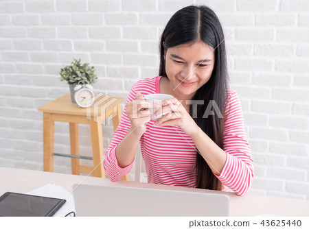 Asian female freelancer smile and drink coffee 43625440