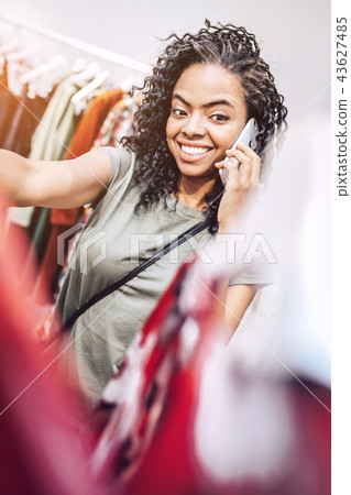 Stylish ethnic woman speaking on phone in shop Stylish ethnic woman speaking on phone in shop 43627485