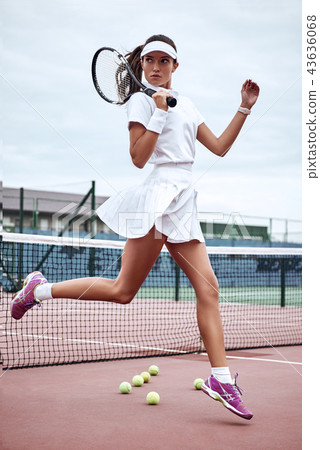Young beautiful sexy sportswoman with tennis racket jumping on tennis court. Sports Fashion Young beautiful sexy sportswoman with tennis racket jumping on tennis court. Sports Fashion 43636068