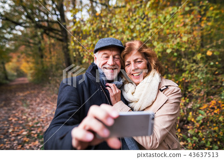 Senior couple in love in an autumn nature, taking selfie. Senior couple in love in an autumn nature, taking selfie. 43637513