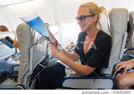 Woman reading magazine on airplane during flight. Woman reading magazine on airplane during flight. 43645805