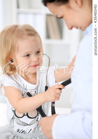 Doctor and patient baby in hospital. Little girl is being examined by pediatrician with stethoscope Doctor and patient baby in hospital. Little girl is being examined by pediatrician with stethoscope 43646040