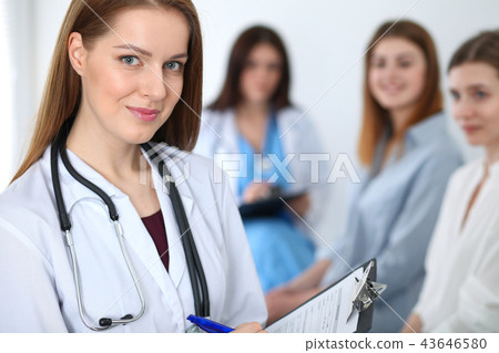 Young beautiful female doctor smiling while consulting her patient. Physician at work. Medicine and Young beautiful female doctor smiling while consulting her patient. Physician at work. Medicine and 43646580