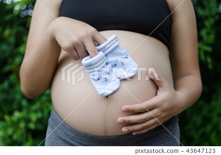 pregnant couple holding baby socks on belly 43647123