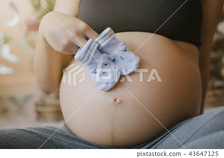 pregnant couple holding baby socks on belly 43647125