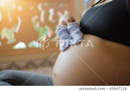 pregnant couple holding baby socks on belly 43647126