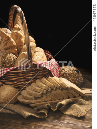 Composition with bread and rolls in wicker basket 43647578