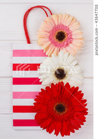 Striped shipping bag and flowers on white background. 43647708