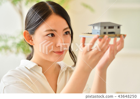 Woman staring at a model of a house 43648250