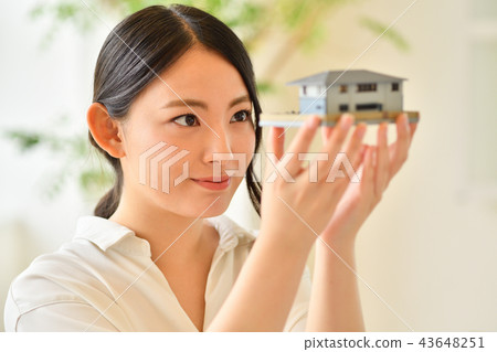 Woman staring at a model of a house 43648251