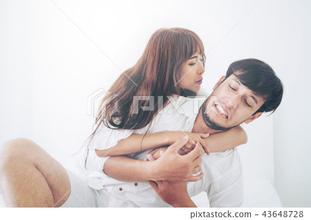 Playful young couple teasing in home bedroom. 43648728