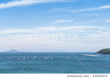 Oyster farm raft floating in the blue sea overlooking the distant island 43648974
