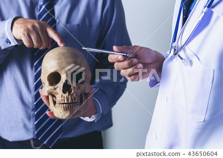 Doctor is holding a human skull in his hands  43650604