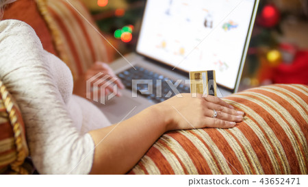 Closeup image of young woman making orders in online store for Christmas Closeup image of young woman making orders in online store for Christmas 43652471