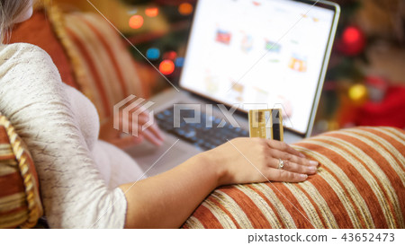 Closeup image of young woman with credit card and laptop making online orders for Christmas Closeup image of young woman with credit card and laptop making online orders for Christmas 43652473