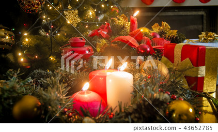 Closeup image of three burning candles against glowing colorful Christmas lights 43652785