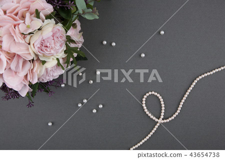 Pearl necklace with rose bouquet over gray background 43654738