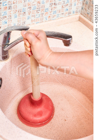 woman clears kitchen sink drain by plunger 43659233