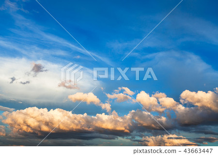 white and yellow cumuli clouds in dark blue sky 43663447