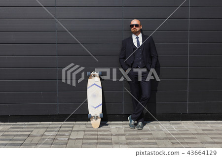 Fashionable business man in perfect suite on the street, using skateboard longboard and sute man Fashionable business man in perfect suite on the street, using skateboard longboard and sute man 43664129