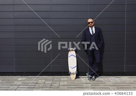 Fashionable business man in perfect suite on the street, using skateboard longboard and sute man 43664133