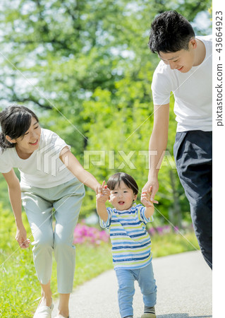 Three-person family playing in a fresh green park 43664923