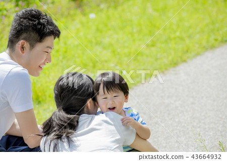 Three-person family playing in a fresh green park 43664932