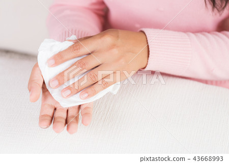 Woman cleaning her hands with a tissue Woman cleaning her hands with a tissue 43668993