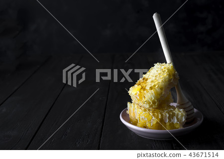 Honey combs with a wooden stick drains honey Honey combs with a wooden stick drains honey 43671514
