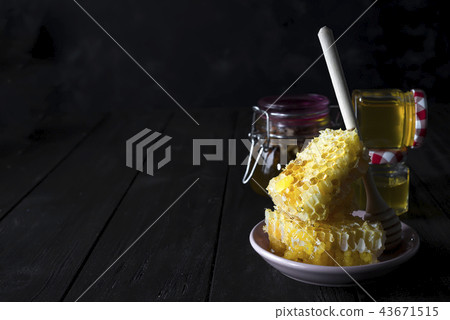 Honey combs with a wooden stick drains honey 43671515