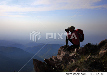 Female tourist taking photo on mountain peak 43672186