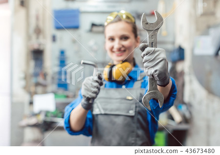 Woman mechanic showing tools to the camera Woman mechanic showing tools to the camera 43673480