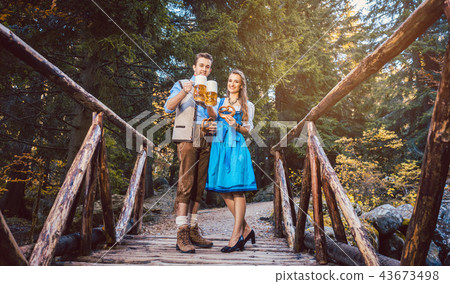 Woman and man with beer standing on bridge in Bavaria 43673498