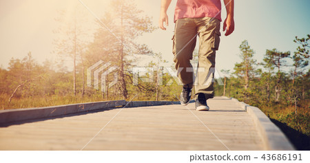 Man walking on wooden walkway in nature 43686191