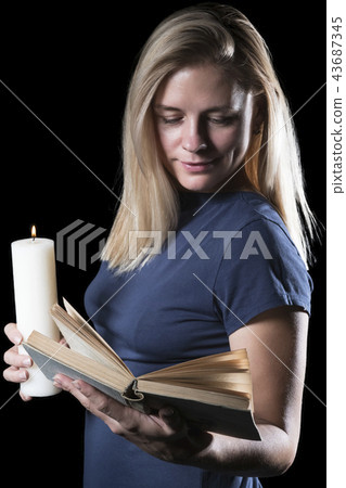 Woman reading a book in the dark Woman reading a book in the dark 43687345