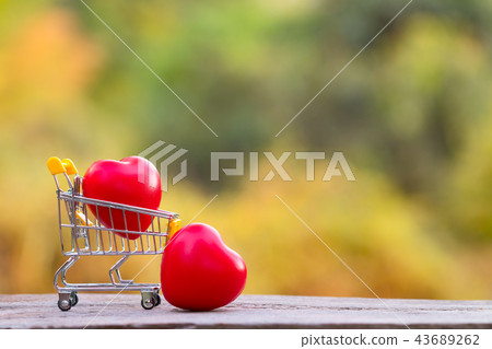 Red heart shape in mini shopping cart on wooden Red heart shape in mini shopping cart on wooden 43689262