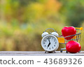 Red heart shape in shopping cart and white clock 43689326