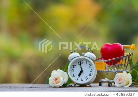Red heart shape in shopping cart and white clock 43689327