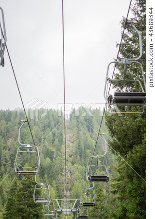 A chairlift with mountains and fog in the back  43689344