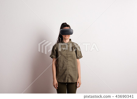 Portrait of a young beautiful woman with VR goggles in studio. Portrait of a young beautiful woman with VR goggles in studio. 43690341