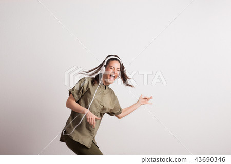 Young woman with headphones, listening to music, singing and pretending to play guitar. Young woman with headphones, listening to music, singing and pretending to play guitar. 43690346