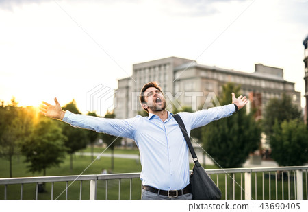 A happy businessman standing on a bridge, screaming and stretching arms. A happy businessman standing on a bridge, screaming and stretching arms. 43690405