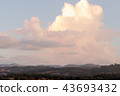 Summer sky filled with sunset colored cumulus clouds over mountains, hills and forest landscape 43693432