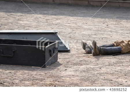 Coffin next to a dead man with his boots 43698252