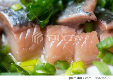 Sliced herring with green onion on a plate. Selective focus macro shot with shallow DOF. 43698390