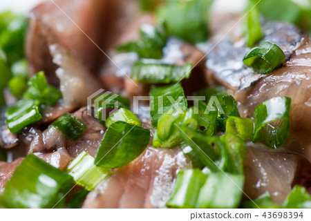 Sliced herring with green onion on a plate. Selective focus macro shot with shallow DOF. Sliced herring with green onion on a plate. Selective focus macro shot with shallow DOF. 43698394