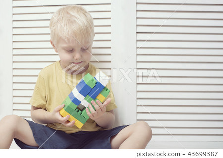 Little blond boy is building of colored designer Little blond boy is building of colored designer 43699387